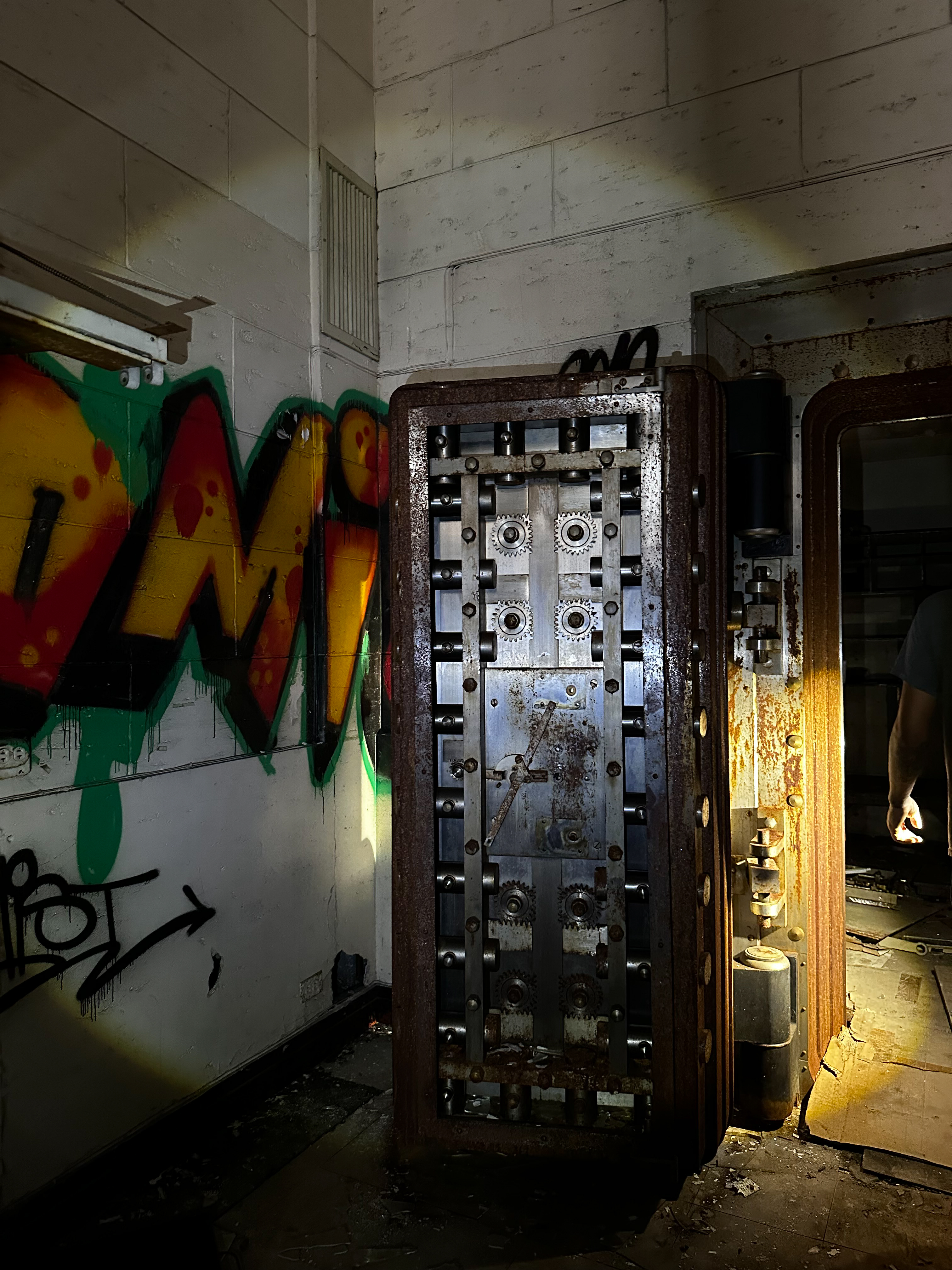 Old vault door in an abandoned bank with graffiti on the walls